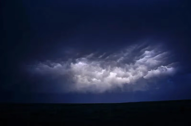 A photograph showing cloud-to-cloud (intracloud) lightning illuminating thunderstorm clouds at nighttime.