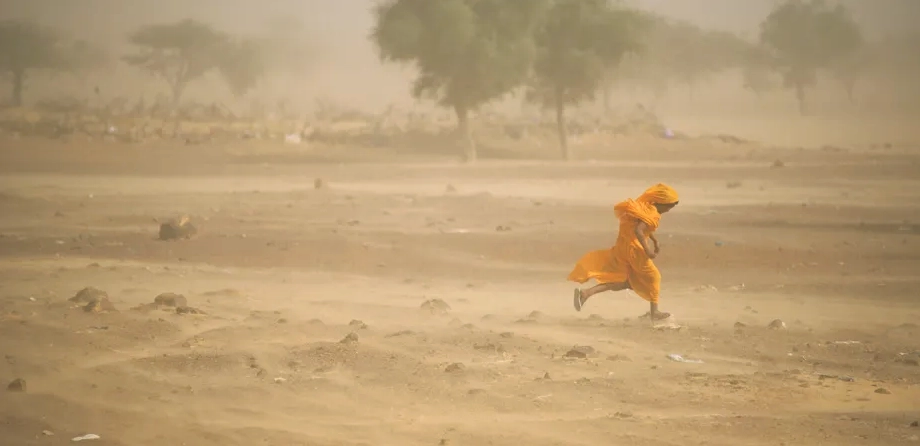 A vast desert landscape with a towering dust storm on the horizon