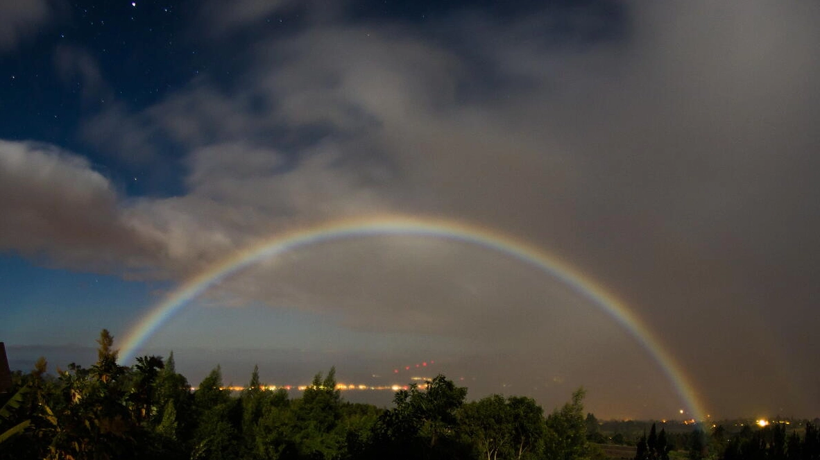 A vibrant moonbow arches over a landscape in Kula, Hawaii