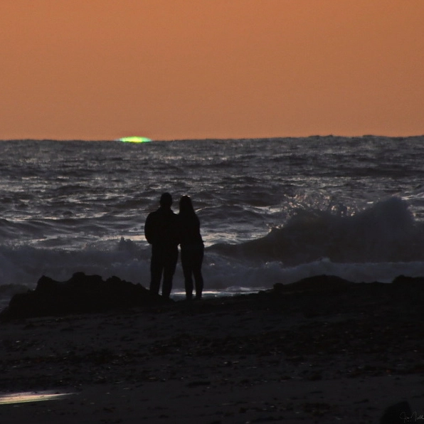 A vivid green flashing light observed at sunset.
