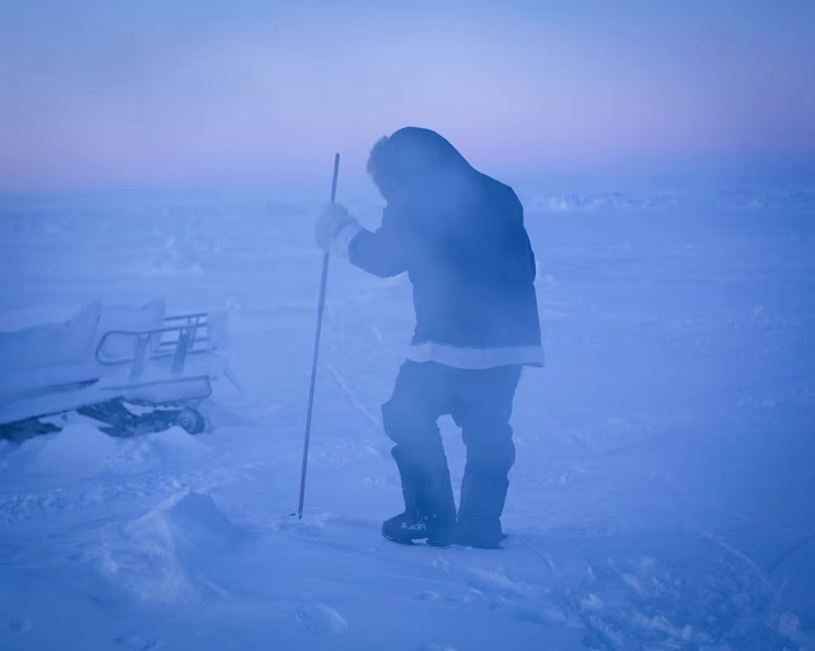 Hunter searching for seals on ice during polar night