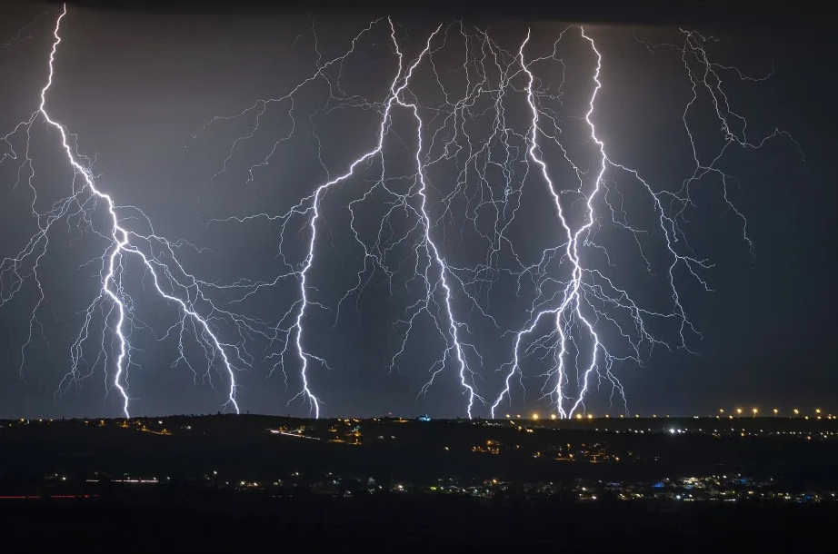 Multiple cloud-to-ground lightning strikes illuminating the night sky during a severe thunderstorm.